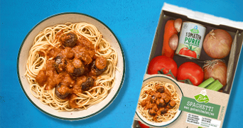 Albert Heijn Biologische Spaghetti maaltijdpakket met gehaktballetjes, inclusief tomatenpuree en verse groenten, geserveerd op een bord.