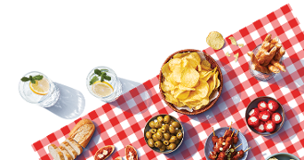 Picknick tafel met aardappelchips, groene olijven, gevulde pepers, stokbrood en drankjes met citroen en munt.