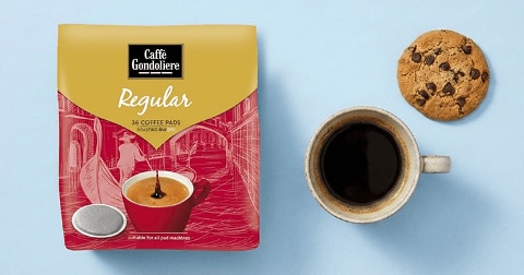 Zak Caffè Gondoliere Regular koffiepads met 36 stuks, naast een kopje zwarte koffie en een chocoladechipkoekje op een lichtblauwe ondergrond.