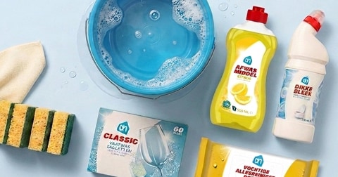 Schoonmaakproducten van Albert Heijn, waaronder afwasmiddel, dikke bleek, vaatwastabletten, vochtige allesreinigerdoekjes, sponsjes en een doekje rondom een schaal met sop.