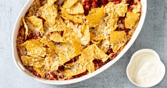 Schaal met nacho's met kaas en tomaat. Samen met een bakje creme freche