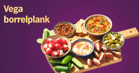 Vegetarische borrelplank met verschillende dips, gevulde pepers, olijven, komkommers, dadels en toastjes op een houten plank, met de tekst 'Vega borrelplank' op een paarse achtergrond