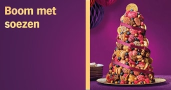 Boomvormige toren gemaakt van soesjes, koekjes en fruit met linten eromheen, gepresenteerd op een paarse ondergrond
