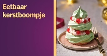 Eetbaar kerstboompje van groene meringue op een bord, gedecoreerd met rode bessen en witte suikerbloemetjes