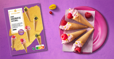 Afbeelding van AH Excellent mini hoornjes naturel, gepresenteerd op een paarse achtergrond. Links is de verpakking zichtbaar met verschillende serveersuggesties, rechts liggen vier hoornjes gevuld met room en frambozen op een roze bord.