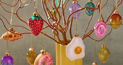 Paastakken versierd met kleurrijke paashangers en papieren eieren in een gele vaas.