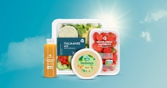 Verschillende Albert Heijn producten zoals Italiaanse salade mix, Nederlandse aardbeien, hummus en verse jus d’orange, gepresenteerd voor een blauwe lucht met zon.