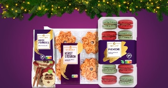 Albert Heijn Excellent kerstmannetjes, kerststerren en macarons verpakt als feestelijke kerstkoekjes op een paarse achtergrond met kerstverlichting