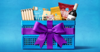 Blauwe Albert Heijn boodschappenkrat gevuld met diverse Albert Heijn huismerkproducten, verpakt met een grote paarse strik als cadeau