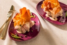 vitello tonnato voorgerecht met gebakken filodeegwaaier op een fuchsia bord gepresenteerd