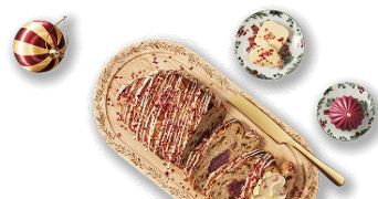 Gesneden kerststol met poedersuiker en amandelspijs op houten serveerplank, erbij een bordje boter met besprenkeling, een paars kerstkaarsje en een rode kerstbal als decoratie