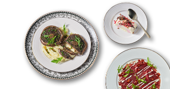 Gerechten op borden met vleesrol op aardappelpuree, carpaccio met rucola en saus, en een dessert met slagroom en granaatappelpitjes