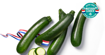 Vier groene courgettes met enkele plakjes, voorzien van het Beter Voor Natuur & Boer keurmerk en een lint in de Nederlandse kleuren