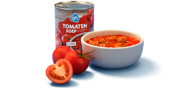 Blik AH tomatensoep naast een kom tomatensoep en verse tomaten