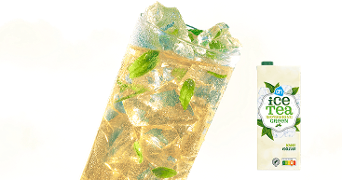 Glas ijsthee met ijsblokjes en muntblaadjes naast een pak AH ice tea green