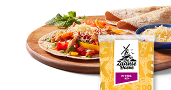 Wrap belegd met groenten en geraspte kaas De Zaanse Hoeve pittig 45+, met extra kaas en wraps op de achtergrond