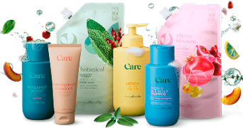 Verschillende flessen en navulverpakkingen van Albert Heijn Care verzorgingsproducten, waaronder douchegel, handzeep, handcrème en shampoo met geuren zoals bergamot, botanical sage, lemon, cardamom comfort, protein rice repair en cherry blossom, uitgestald met fruit en kruiden ter decoratie