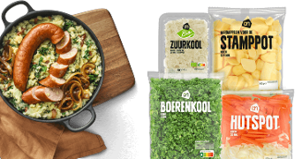 Boerenkool stamppot met rookworst in een pan op een houten plank, naast verpakkingen van Albert Heijn met zuurkool, aardappelen voor stamppot, boerenkool en hutspotgroente.