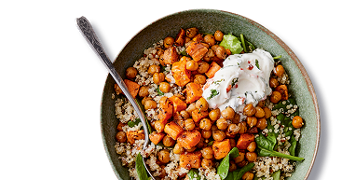 Bord met zoete aardappel, kikkererwten, couscous, spinazie en een sausje