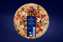 Pizza van het merk D'ORO culinair met verse toppings, zoals rode ui, paprika en kruiden, verpakt in een ronde verpakking tegen een blauwe achtergrond.