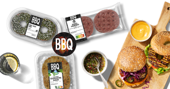 BBQ producten met AH vleesvervanger en runderhamburgers, inclusief een geserveerde burger met rode kool en sla op een houten plank.