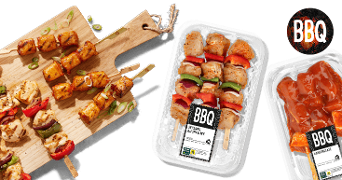 Kipsaté- en kipsouvlaki-spiesen op houten plank en verpakt als BBQ-producten van Albert Heijn, met paprika en ui