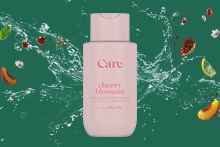 Care cherry blossom douchegel fles met fruit en water splash op groene achtergrond