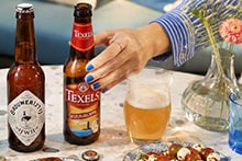 IJwit en Texelse Skuumkop op tafel met glas bier en hand.