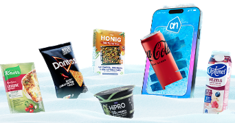 Knorr lasagne mix, Doritos Sweet Chili Pepper chips, Honig bakplaatmix, HiPRO yoghurt, Coca-Cola Zero Sugar, en Optimel vezelrijke drink naast een smartphone met Albert Heijn app, geplaatst in een besneeuwde setting.