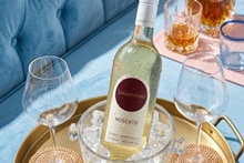 Fles Samaniego Moscato witte wijn gekoeld op ijs met twee wijnglazen op een gouden dienblad