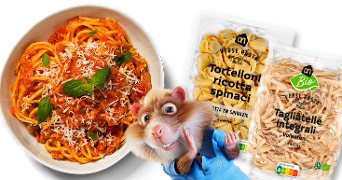 Bord met Italiaanse pasta met tomatensaus en basilicum, naast verpakkingen AH Verse Pasta Tortelloni ricotta spinaci en AH Bio Tagliatelle Integrali, met een vrolijke animatiehamster als mascotte.