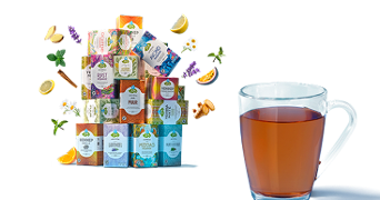 Piramide van verschillende Albert Heijn kruidenthee verpakkingen, omringd door kruiden, specerijen en fruit, naast een glas met warme thee.