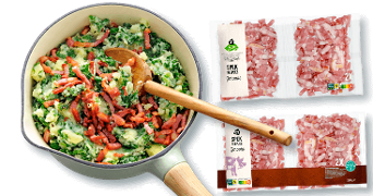 Hollandse stamppot boerenkool met gebakken spekjes in een pan, naast twee verpakkingen AH gerookte spekreepjes.