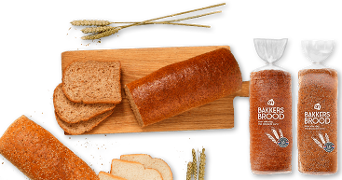 Volkoren brood van Albert Heijn, gesneden en in verpakking, met enkele tarwehalmen op een houten plank.