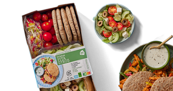 Griekse maaltijdpakket met pita gyros, salade met tomaat, komkommer, olijven en feta, en een bord met pita’s, gyros en saus.