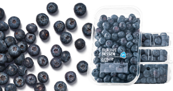 Doosjes met blauwe bessen van Albert Heijn naast losse blauwe bessen.