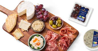 Borrelplank met diverse kazen, druiven, olijven, vleeswaren en dips, aangevuld met Albert Heijn Excellent Medjoul dadels en Excellent oude kaas truffelspread.