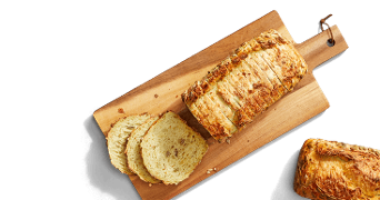 Gesneden meergranenbrood op een houten plank, met enkele losse sneetjes ernaast.