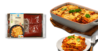 AH lasagne maaltijdpakket met verpakte ingrediënten, daarnaast een ovenschaal met gebakken lasagne en een bord met een portie lasagne, gegarneerd met verse basilicumblaadjes.