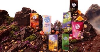 Verschillende Delicata chocoladerepen tentoongesteld tussen stukken pure chocolade, noten, fruit en chocoladestroom op de achtergrond.