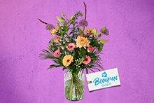 Boeket bloemen in een glazen vaas met Albert Heijn Bloeman kaart, op een paarse achtergrond