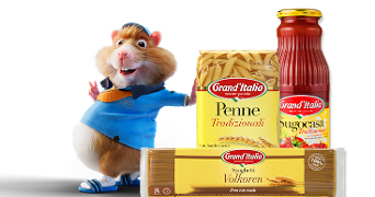 Albert Heijn hamstermascotte naast Grand'Italia Penne Tradizionali pasta, Spaghetti Volkoren en Sugocasa Tradizionale pastasaus