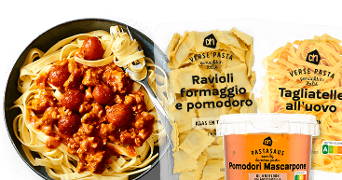 Pasta met vleessaus in een kom, naast verpakkingen van Albert Heijn verse ravioli formaggio e pomodoro, tagliatelle all'uovo en pastasaus pomodori mascarpone