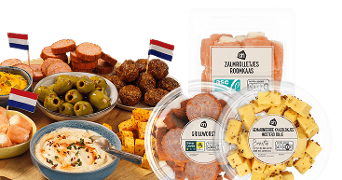 Assortiment van borrelhapjes, waaronder zalmrolletjes met roomkaas, grillworst, gemarineerde kaasblokjes, olijven, en dipsaus, gepresenteerd met Nederlandse vlaggetjes, van Albert Heijn.