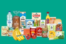 Een selectie van Albert Heijn producten, waaronder brood, bananen, appels, ontbijtgranen, kaas, eieren, water, yoghurt, tomaten, olie, en andere dagelijkse boodschappen, gepresenteerd tegen een groene achtergrond.