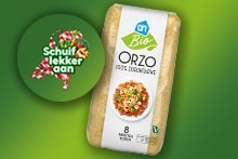 AH Biologische Orzo pasta verpakking op groene achtergrond, met een ronde sticker waarop staat "Schuif lekker aan".