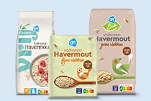 Drie verschillende verpakkingen Albert Heijn volkoren havermout, waaronder glutenvrij en biologische varianten