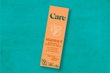 Care vitamine K druppels verpakking op een turquoise achtergrond
