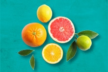 Verschillende citrusvruchten op een turquoise achtergrond, waaronder een sinaasappel, citroen, grapefruit en limoen.