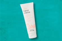 AH Care handcrème tube op een turquoise achtergrond